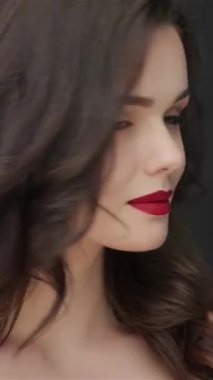 Hoş, genç bir kadın dalgalı siyah saçlarıyla bir öpücük yolluyor büyüleyici gülüşü parlak, siyah bir arka plana sıcaklık saçıyor. Bu çarpıcı portre onun kusursuz cildini ve kalın kırmızı dudaklarını ön plana çıkarıyor. Her yerde kendine güveni ve cazibesi var.