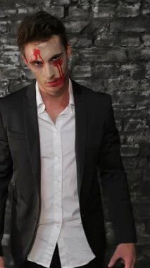 Parlak siyah bir takım elbise giymiş uğursuz bir vampir, desenli siyah tuğla bir duvara yaslanıyor, solgun yüzü kan lekeleri ve ürpertici bir bakışla işaretlenmiş. Bu rahatsız edici görüntü Cadılar Bayramı 'nın özünü özetliyor, korku ve entrikayı onunla harmanlıyor.