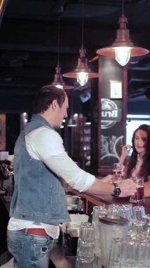 Sıcak, davetkar ışıklarla aydınlatılmış canlı bir barda, üç arkadaş canlısı, neşeli genç kadın ve güler yüzlü bir barmen içkilerini sıcak bir barmenden alır. Gülüşleri ve hareketli sohbetleri neşeli bir atmosfer yaratıyor, kutlama yapıyorlar.