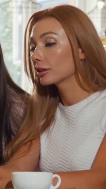 Enfes bir kahve dükkanında, iki bayan arkadaş akıllı telefonlarıyla büyülenir, kahkahalarını ve heyecanlarını paylaşırlar. Işıl ışıl kızıl saçlı kadın en iyi arkadaşına büyüleyici bir şey gösteriyor. Sıcak ve davetkar bir atmosfer yaratıyor.