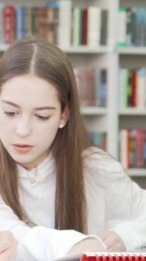 Kendini derslerine adamış iki genç kız, canlı bir kütüphanede renkli kitapların olduğu bir kaleydoskop içinde bir ödev üzerinde çalışıyorlar. İfadeleri konsantrasyon ve neşe saçıyor, dostluğun ve takım çalışmasının özünü yakalıyor.