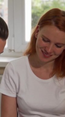 Canlı, kızıl saçlı genç bir iş kadını neşe içinde gözlüğünü çıkarırken kendine güven ve cazibe saçıyor. Hareketli ofis arkaplanı, nişanlısının iş birliği yaparak yaratıcılığın dinamik atmosferini teşvik ettiğini gösteriyor.