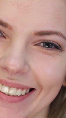 Çekici bir yakın plan, beyaz tenli güzel bir kadın, sıcak ve davetkar bir gülümseme. Kusursuz yüzüne yaptığı nazik dokunuş doğal güzelliğini vurgular, saf beyaz arka plan ise zarafeti ve saflığı arttırır.