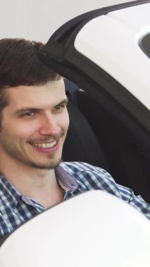 Işıldayan genç bir adam üstü açık arabasında otururken mutluluk saçıyor, gururla araba anahtarlarını başarıyla gösteriyor. Bu canlı sahne, yeni mülkiyetin neşesini ve açık ruhun özgürleştirici ruhunu özetliyor.