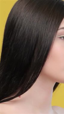 Büyüleyici bir Asyalı kadın şakacı bir şekilde parmağını dudaklarına bastırıyor, parlak sarı arkaplana karşı sessizliği davet ediyor. Uzun, pürüzsüz saçları zarif bir şekilde akıyor, büyüleyici cazibesini arttırıyor ve izleyicileri keyifli dünyasına davet ediyor.