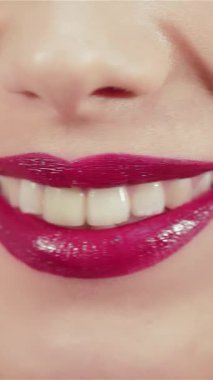 Bu büyüleyici yakın plan güzel genç bir kadının büyüleyici, ışıltılı dudaklarını göz kamaştırıcı bir gülümsemeyle aydınlatıyor. Kusursuz cildine ve canlı rujunun ışıldayan renklerine odaklanması davetkar bir atmosfer yaratıyor.