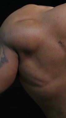 Bu büyüleyici yakın plan gösterileri, kendini adamış bir erkek vücut geliştiricinin, belirgin kasları ve çarpıcı siyah bir zemine karşı çetrefilli dövmeleri vurguluyor. Görüntü fitness ve bağlılık ruhunu somutlaştırıyor, hayranlık uyandırıyor.