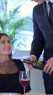 Genç ve şık bir çift şık bir restoranda kutlama yaparken, koca karısına bir bardak koyu kırmızı şarap dolduruyor. Yumuşak, romantik bir ışıkla yıkanmış ve yemyeşil bir ortamda, kahkahalarla ve şefkatleriyle çevrelenmiş.