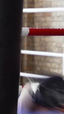 Kararlı genç bir erkek boksör, üstsüz ve dövmeli, ağır bir torbaya güçlü yumruklar savuruyor, ham kuvvet ve odaklanmayı somutlaştırıyor. Boks salonunun eskimiş teçhizatı ve enerjik enerjisiyle kumlu ambiyansı, yoğunluğu arttırır.