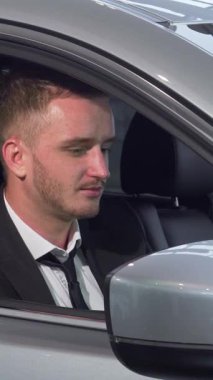 Şık bir saç kesimi ve keskin takım elbisesi olan kendine güvenen bir iş adamı galeriden aldığı şık yeni arabasının anahtarlarını elinde tutuyor. Bu dinamik sahne heyecan ve başarı yayar, sahip olmanın ve eğlencenin heyecanını yansıtır.