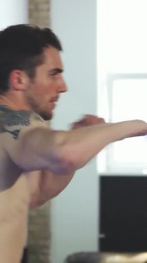 Kararlı, genç, kaslı bir erkek boksör güneşli bir spor salonunda güçlü yumruklar atıyor, kendini adamış ve atletik hüner gösteriyor. Çarpıcı dövmesi eğitiminin vahşi enerjisini arttırıyor, dinamik hareketlerdeki bir şampiyonun ruhunu somutlaştırıyor.