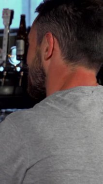 Gri tişörtlü şık bir genç adam, samimi bir barda arkadaşıyla samimi bir kahkaha atıyor. Her biri soğuk bir bardak biranın tadını çıkarıyor. Sıcak ışık ve dostça sohbetlerle dolu davetkar atmosfer mükemmel bir ortam hazırlıyor.