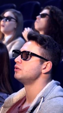 Üç boyutlu gözlük takan çeşitli genç yetişkinlerden oluşan bir grup, rahat bir sinemada canlandırıcı bir film karşısında büyüleniyor. Sarışın adam heyecanla ışıldarken, Asyalı kadın öne eğiliyor, gözleri merakla parlarken,