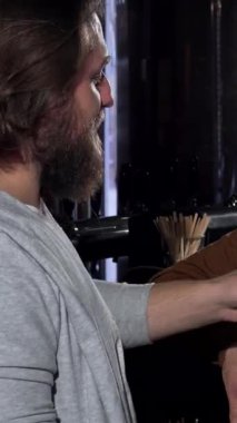 Hareketli bir barda, neşeli bir arkadaş üçlüsü göz kamaştırıcı bir kadın ve iki erkek arkadaş bardaklarını köpüklü el yapımı bira ile tokuşturarak Oktoberfest 'in şenlik ruhunu somutlaştırıyorlar. Bar ışıklarının sıcak, davetkar parıltısı ışıltılarını vurguluyor.