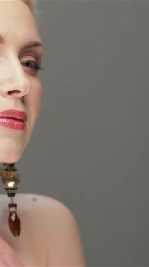 Kafkasyalı güzel bir kadının büyüleyici portresi yumuşak gri bir arka plana zarafet saçıyor. Kusursuz cildi yüzünü nazikçe okşayarak parıldıyor zarif cazibesini ve sofistike cazibesini arttıran zarif küpeleri vurguluyor.