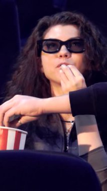 Sakallı neşeli sarışın bir adam sıcak bir sinemada arkadaşlarıyla çevrili canlı çizgili patlamış mısır kovasına hevesle uzanır. Üç boyutlu gözlük takan kıvırcık saçlı bir kız hareketli bir şekilde sohbet ediyor, havayı kahkaha ve heyecanla dolduruyor,