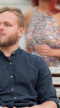 Neşeli bir kız, partnerini öpmek için eğildiğinde, canlı bir şehir plaj zeminine karşı saf bir şefkat anı yakalar. Kaygısız ruhları şehrin hayat dolu enerjisiyle çevrili sıcaklık ve mutluluk saçıyor.