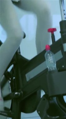 Enerjiyle dolu canlı bir spor salonunda, iki genç bayan spor bisikletleriyle neşeyle pedal çeviriyor, onların ışıl ışıl gülümsemeleri dostluk ve zindelik ruhunu yansıtıyor. Bu canlı sahne, renkli spor salonlarıyla çevrili atletik figürlerini hareket halinde yakalıyor.