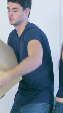 Neşeli bir çift, bir erkek ve bir kadın, güneşli yeni dairelerinde, el değmemiş beyaz duvarlar ve rahat bir kanepe ile çevrili kutuları neşeli bir şekilde taşıyorlar. Parlak gülümsemeleri ve neşeli enerjileri yeni başlangıçların heyecanını, somutlaştıran aşkı ve