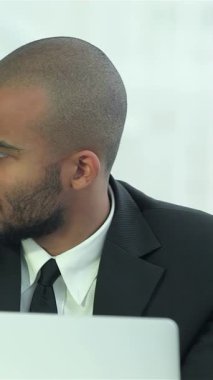 Gösterişli, modern bir ofiste, biri koyu saçlı, diğeri sakallı iki genç adam, yoğun bir şekilde dizüstü bilgisayarda gösterilen görüşleri tartışıyorlar. Kararlı ifadeleri ve keskin iş kıyafetleri sinerjiyi vurguluyor