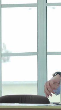 Pürüzsüz, güneşli bir ofiste, resmi giyinmiş iki dinamik işadamı güven dolu bir tokalaşma ile umut verici bir ortaklık kuruyor. İfadeleri pozitifliği ve kararlılığı gözler önüne seriyor. Etrafı parlak bir masa ile çevrili.