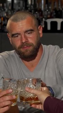 Neşeli, olgun bir adam viski bardağını kaldırır ve bir barda gülüşlerini ve dostluklarını paylaşan arkadaşlarıyla kadeh kaldırır. Bar ışıklarının sıcacık parıltısı ve bardakların tıkırtısı dostluğu kutlamak için davetkar bir atmosfer yaratıyor.