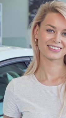 Kendinden geçmiş bir kadın, arabasının anahtarlarını gururla sergileyerek rüya aracını satın alışını kutluyor. Gösterişli arabalar ve profesyonel bir satış elemanı ile dolu canlı bir galeri, bu zaferin heyecanını arttırıyor.