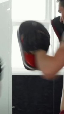 Sırtında çarpıcı bir dövme olan kaslı bir erkek MMA dövüşçüsü, güçlü bir direnç ve odaklanmaya yoğun bir şekilde hazırlanıyor. Atmosfer enerjiyle dolu, sporcuların kendilerini adamışlıklarını ve tutkularını vurguluyor.