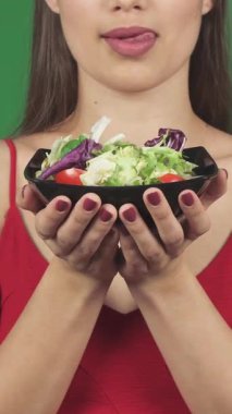 Çekici, genç bir kadın, tatlı dudaklarıyla onları şakayla yalıyor, ellerinde canlı bir kase taze salata tutuyor. Bu baştan çıkarıcı yakın çekim sağlık ve şehvet saçıyor, izleyicileri lezzetli ve besleyici bir yaşam tarzının tadını çıkarmaya davet ediyor.