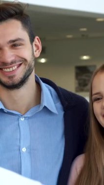 Neşeli bir çift, coşkulu satıcıdan parlak araba anahtarını alan kadının ışıl ışıl ışıl ışıl ışıldıyor. Yanındaki kendine güvenen adam cazibesini sergilerken, canlı atmosfer heyecanla ve umutla uğulduyor.