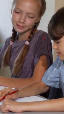 Canlı bir sanat dersinde, neşeli bir oğlan ve yaratıcı bir kız canlı hayal güçlerini kağıt üzerinde hayata geçirirken aynı zamanda animasyon sohbetlerini paylaşırlar. Şık saç kesimi ve odaklanmış ifadesiyle oğlan dikkatle resim çizerken, kız spor yapıyor.