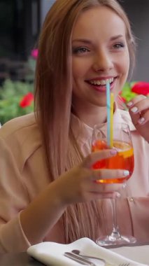 İki ışıl ışıl kadın güneşin tadını çıkarıyor, gülüşlerini paylaşıyorlar ve çiçeklerle süslenmiş canlı bir terasta ferahlatıcı kokteyller içiyorlar. Neşeli kavuşmaları arkadaşlığın sıcaklığını ve yaz öğleden sonralarının mutluluk dolu özünü özetliyor.