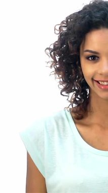 Büyüleyici kıvırcık saçlı Afro-Amerikalı bir kız yukarı işaret ederken neşe saçıyor, ilham ve pozitifliği somutlaştırıyor. Parlak gülüşü ve ışıl ışıl gözleri çekici bir portre yaratıyor, parlak beyaz bir arka plana karşı gençlik cazibesi yayıyor.