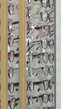 Şık sakallı, şık bir genç adam şık bir optometri dükkanındaki şık gözlükleri tutkuyla fotoğraflıyor. Parlak ışıklarla aydınlatılan hareketli çerçeveler canlandırıcı bir alışveriş atmosferi yaratıyor.