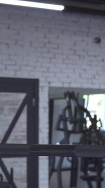 Enerjik genç bir sporcu kadın spor salonunda dinlenirken neşe saçıyor. Cildi parlak, enerjik ışıkların altında ter içinde parlıyor. Bu kendini adamış sporcu, zindelik ve refahına olan bağlılığını göstererek güç ve canlılığı somutlaştırıyor.