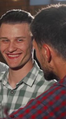 Yakışıklı erkek arkadaşlardan oluşan canlı bir toplantı, keyifli bir şekilde bira bardaklarını tokuşturur, kahkaha ve dostluk dolu bir barda eğlenirler. Sıcak ışıklandırma ve kırsal dekor ile zenginleşen davetkar atmosfer, iş sonrası keyiflerini güçlendiriyor.