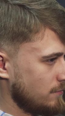 Bu yakın plan, yetenekli bir berber moda saç kesimini titizlikle şekillendirirken kendine güveni yayan yakışıklı bir genci gösteriyor. Modern dekor ve enerjik enerjiyle dolu şık bir berber ortamı, sanatın ve hassasiyetin altını çiziyor.