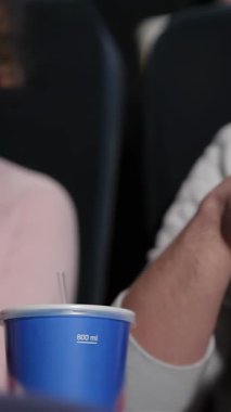 Neşeli bir çift, lüks bir sinemada keyifli bir film gecesinin tadını çıkarıyor, büyük bir kova patlamış mısır paylaşıyor ve serinletici içeceklerden yudumluyor. Gülüşleri ve heyecanları sıcak, davetkar bir atmosfer yaratıyor. Romantik bir randevu gecesi için mükemmel.