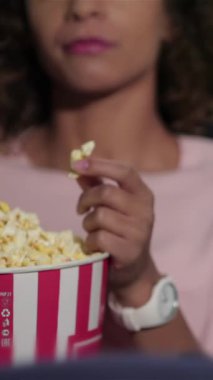 Neşeli bir çift, lüks bir sinemada büyük bir kova patlamış mısırın tadını çıkarıyor. Kahkahaları havada yankılanıyor ve kendilerini filmlerin büyüsüne kaptırıyorlar. Sıcak atmosfer, yumuşak kırmızı ve mavi tonlarıyla, neşeli bağlantılarını güçlendirir,