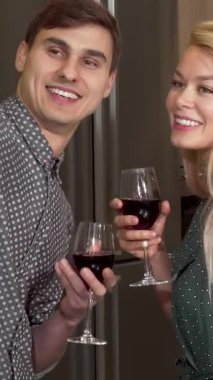 Neşeli bir çift, bir erkek ve bir kadın, sevgililer gününde aşklarını kutlarken şık dairelerinde selfie çekerken kırmızı şarap kadehlerini tokuştururlar. Şık dekor ve sıcak ışık davetkar bir atmosfer yaratıyor, neşe saçıyor ve...