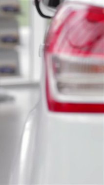 Rahat bir süveter içinde şık bir genç kadın parlak, modern bir bayilikte şık bir model arabayı inceliyor ve otomotiv tercihleri için heyecan saçıyor. Sergi salonu enerji ile uğulduyor, parlayan araçlar onun tutkusunu yansıtıyor.