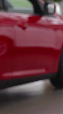 Rahat bir süveter giyen şık bir genç kadın, parlak ve modern bir bayide çarpıcı bir model arabayı hevesle inceliyor ve otomotiv seçenekleri için heyecan saçıyor. Parlak araçlar ve çağdaş tasarımlarla süslenmiş canlı sergi salonu,