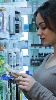 Sıcak bir gülümseme ile mutlu genç bir kadın renkli eczane rafları arasında duruyor, bir dizi sağlık ve güzellik ürününü dikkatlice inceliyor. Bu canlı sahne, perakende terapinin neşesini yayıyor. Ürünleri seçerken heyecanını vurguluyor.