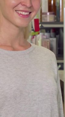 Parlak bir gülümsemesi olan neşeli bir kadın hareketli eczanede kendi seçimiyle tatmin olduğunun sinyalini veren canlı yeşil haplardan oluşan bir paket sergiliyor. Renkli eczane arka planı sağlık ve sağlık atmosferi yayıyor.