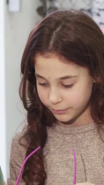 Hoş bir yakın plan çekimde güzel bir genç kadın ve sevimli küçük kız kardeşi canlı bir gözlük mağazasında şık güneş gözlüğü denerken neşe saçıyorlar. Neşeli gülüşleri ve renkli göz kıyafetleri canlı bir atmosfer yaratıyor.