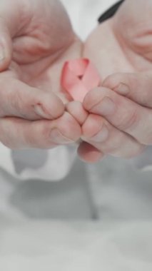 Şefkatli bir doktor ellerinde narin pembe bir kurdele tutuyor. Meme kanserine karşı verilen mücadelede umudu ve dayanışmayı simgeliyor. Bu içten görüntü, erken teşhis ve kendini sorgulamanın hayati önemini vurgular, ilham verir.