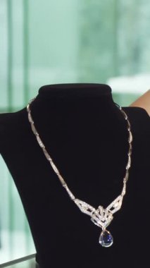 Göz alıcı, kızıl saçlı bir kadının büyüleyici yakın çekimi. Gözleri neşe içinde ışıldıyor. Lüks bir mücevher mağazasında zarif bir şekilde sergilenen nefes kesici elmas kolyeye hayran. Gösterişli atmosfer, yumuşak ışıklandırma ve gösterişli