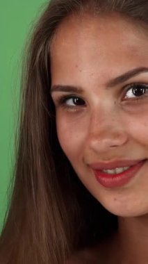 Canlı bir stüdyo, parlak tenli genç bir kadını canlı bir portakalı parlak yeşil zemin üzerinde tutarken kameraya neşeyle ışıldarken görüntüler sergiliyor. Bu görüntü pozitif ve yaşam sevinci yayar, izleyicileri kucaklamaya teşvik eder.