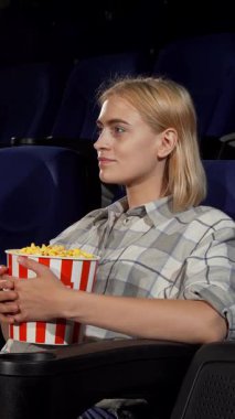 Neşeli bir gülümsemesi olan ışıl ışıl genç bir kadın, elinde canlı bir kova patlamış mısırla lüks bir sinema koltuğunda rahatça oturur. Sıcak daveti sizi tiyatronun sıcak ortamında unutulmaz bir film deneyimi için ona katılmaya davet ediyor.