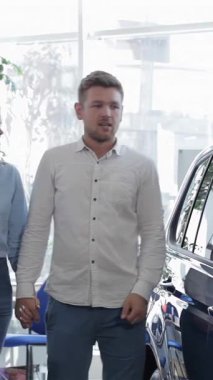 Şık bir çift galeride parlak mavi bir SUV 'ye yaklaşırken, çekici adam kız arkadaşına hareketli bir şekilde özelliklerini anlatıyor. Güzel esmer kadın, bu heyecan verici arabayı paylaşırken şefkatle omzuna yaslanıyor ve mutluluk saçıyor.